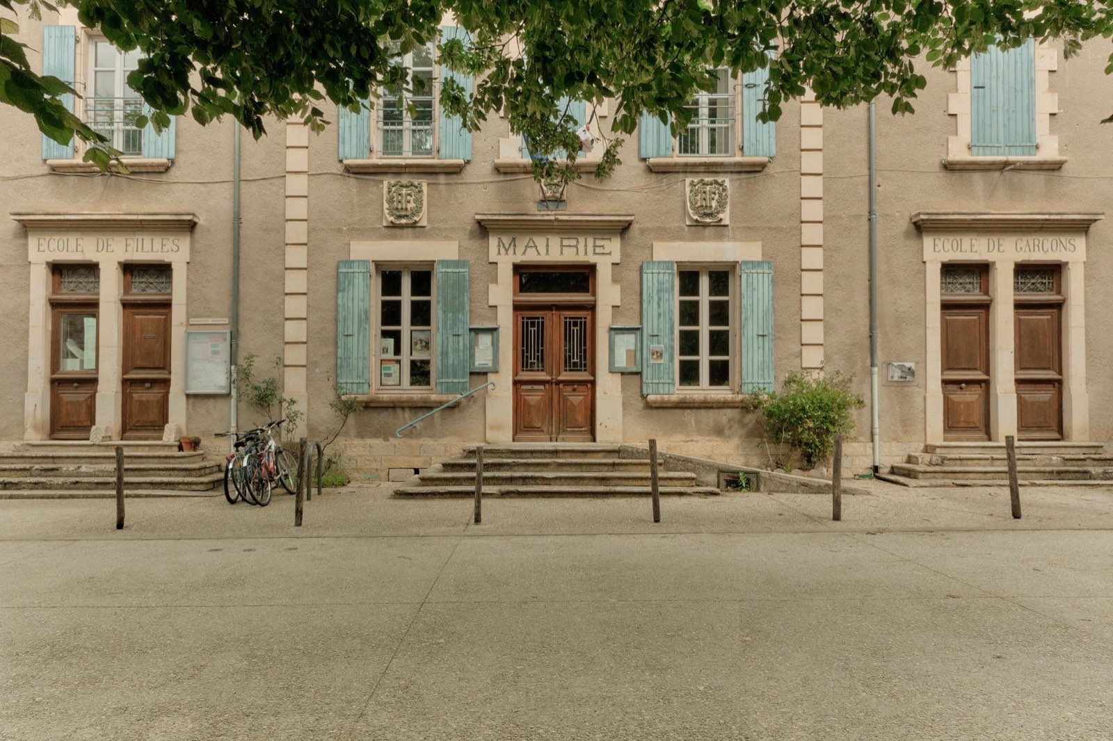 Façade d’une mairie provençale portant les inscriptions gravées « École de filles », « Mairie » et « École de garçons ».